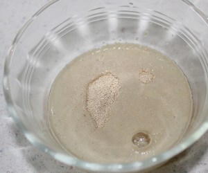 While milk is cooling, add yeast to 1/4 cup lukewarm water, stir until yeast is dissolved then leave it alone to do its thing for a few minutes while the milk cools.