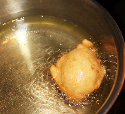 Heat about four cups of oil in a heavy saucepan (you want a couple inches of oil in there) and heat over medium-high heat until a bit of dough dropped in sizzles. Drop a heaping spoon of dough (carefully!) into the oil and fry until golden brown. These sweet little babies turn themselves over so you don't have to, unless you want to, then by all means- go right ahead!