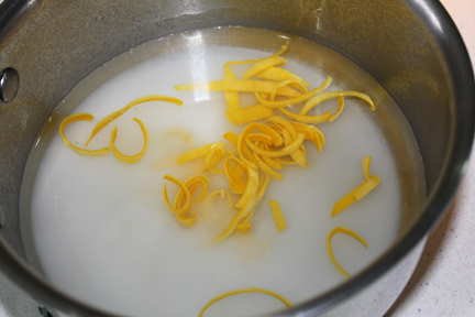Add 1/2 cup of sugar and another cup of cold water to the peel and bring to a boil, stirring with a wooden spoon to dissolve sugar.
